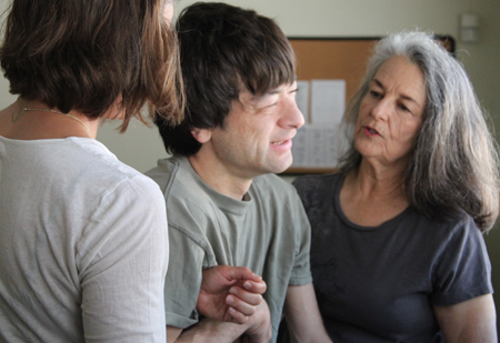 Two instructors assist a male participant with dark hair and light skin.