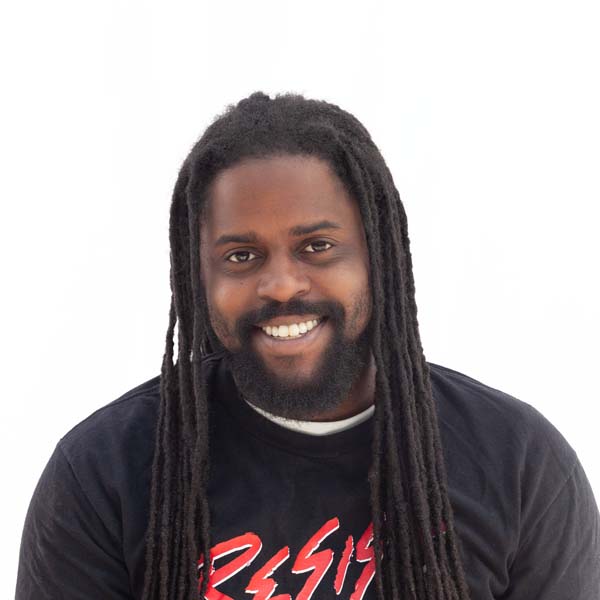 Headshot of Harry Gibbs, a Black man with a short n;acl beard and long braided black locks.