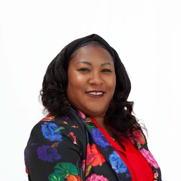 Headshot of Stefanee Hardaway, an African-American woman with brown skin, brown eyes, and black hair. She is wearing a colorful floral print jacket over a red shirt.