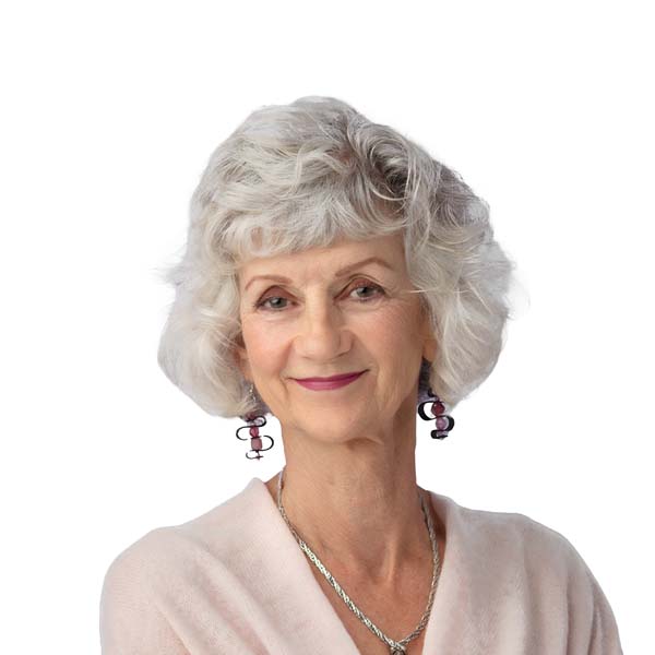 Profile Image of Jan Hetherington, a White woman with a gray bouffant hairstyle wearing an off-white cartigan and prominent jewelry.