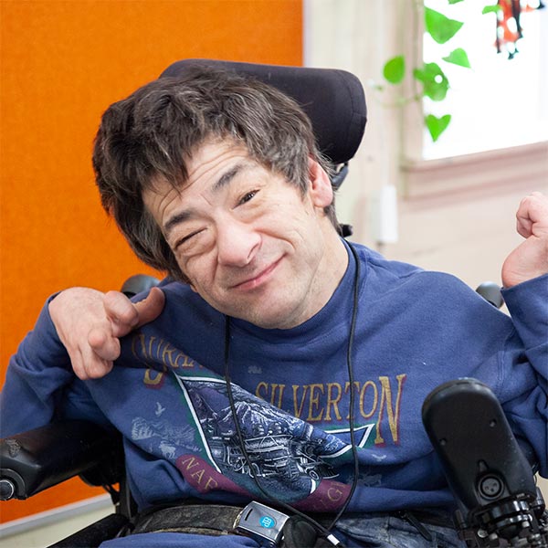 Profile image of Kevin, a light-skinned multi-ethnic individual with brown hair. They are seated in a power chair and wearing a blue sweatshirt.