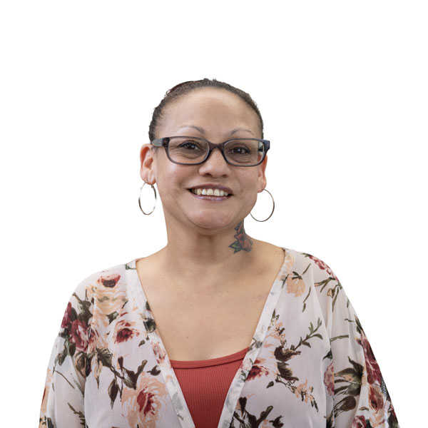 Profile image of Michelle Rodrigues, a Latina woman with her dark hair tied back. She is wearing hoop earings and a floral patterned blouse and has a floral tattoo on her neck.
