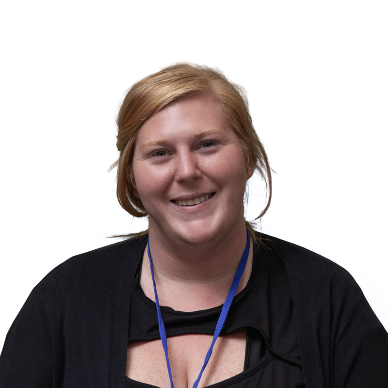 profile image of Lacey Frietas, a light skinned woman with red-blond hair wearing a black shirt and blkue lanyard